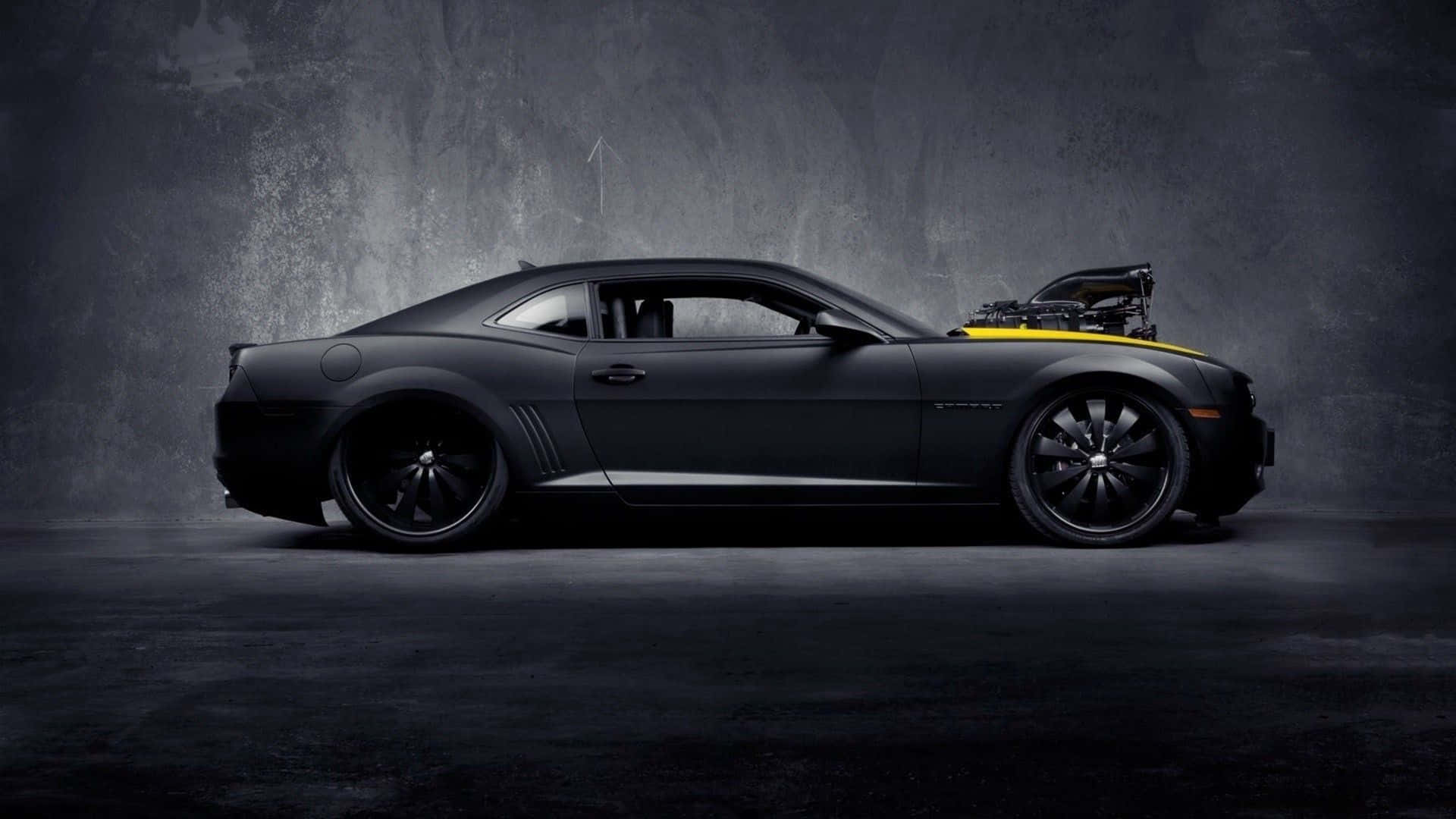 A matte-black muscle car lit in a studio